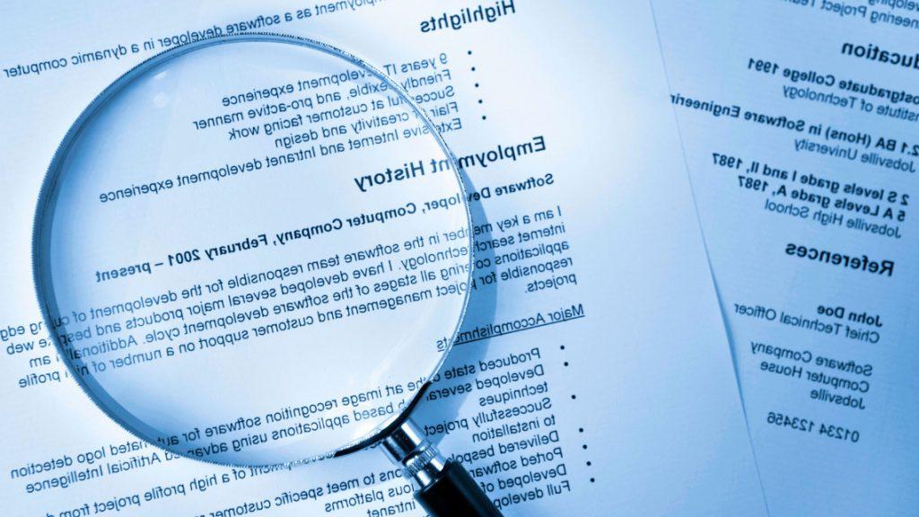 Magnifying glass resting on top of resumes